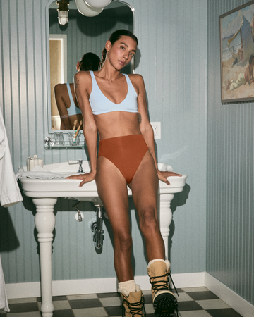 Woman standing in Plunge top in coconut with hi hi bottom in tan lines