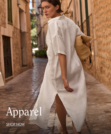 Woman in a white Getaway Shirt Dress walking down a narrow street with 'Apparel' and 'Shop Now' text.