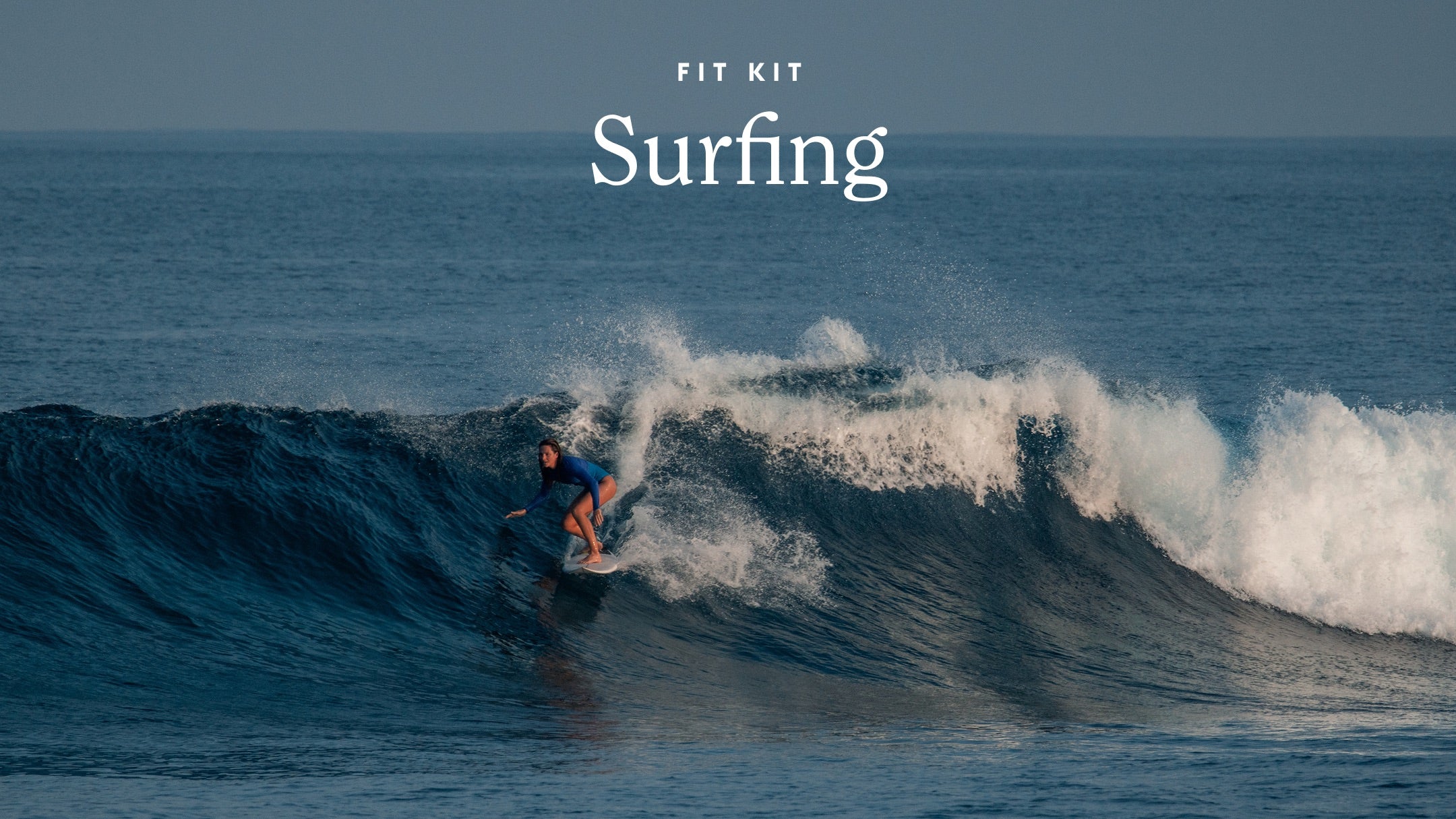A surfer rides a large ocean wave under a clear sky, with the text 'FIT KIT Surfing' overlaid at the top center.