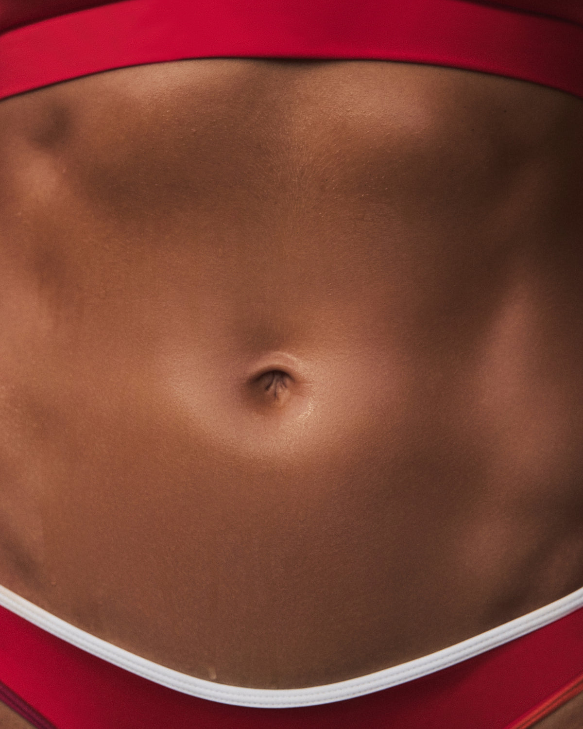 Close-up of a person's midsection wearing red athletic bottoms with a white trim.