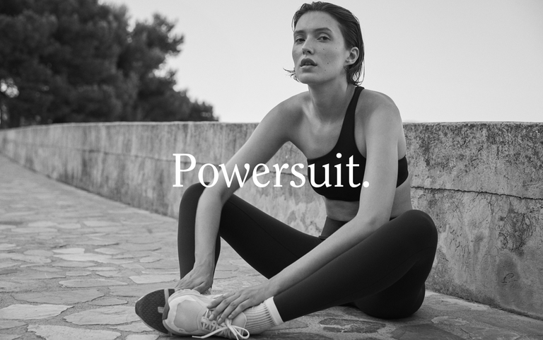 Woman in Offshore top + Super Moves Tight in Jet sitting on a stone wall with 'Powersuit' text overlay.