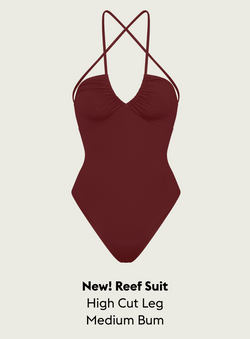 Jam (Maroon) Reef Suit with criss-cross straps on a beige background