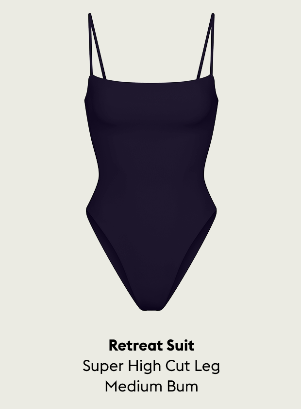 Navy Retreat suit with super high cut leg and medium bum on a light beige background
